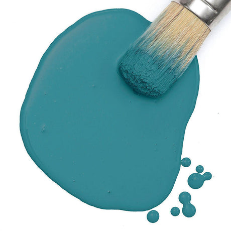 Fusion Mineral Paint Poolside Milk Paint brush resting on a blue-green paint puddle with small splatters nearby.