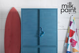 Cabinet painted in Poolside Milk Paint by Fusion next to a red surfboard; wall above painted to match.