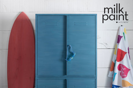 Cabinet painted in Poolside Milk Paint by Fusion next to a red surfboard; wall above painted to match.