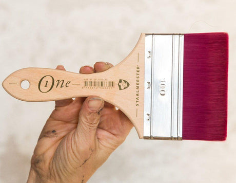 Hand holding Staalmeester Spalter Flat Blending Ultimate ONE Synthetic Paintbrush 1050 with pink bristles.